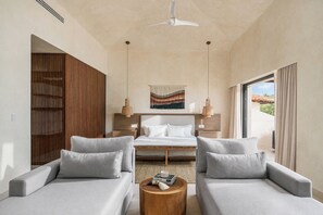 A modern hotel room with a bed, two sofas, a round wooden table, and a view of the outdoors. - Best value in Punta Mita! Fully Remodeled 3 bed Luxury Villa w/ Staff, Golf Cart (Punta Mita)