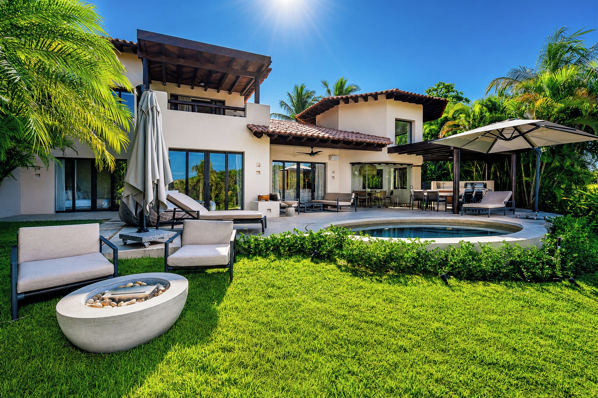 Uma casa moderna com piscina, área de estar externa e vegetação exuberante.