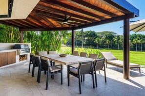 Eine Terrasse im Freien mit Esstisch, Stühlen und Grill.