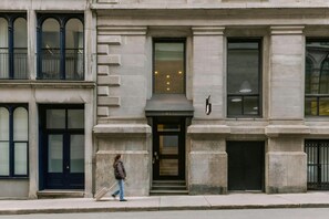 Un edificio de estilo arquitectónico clásico, que presenta una entrada destacada con una puerta negra, ventanas grandes y un balcón con barandillas de metal.