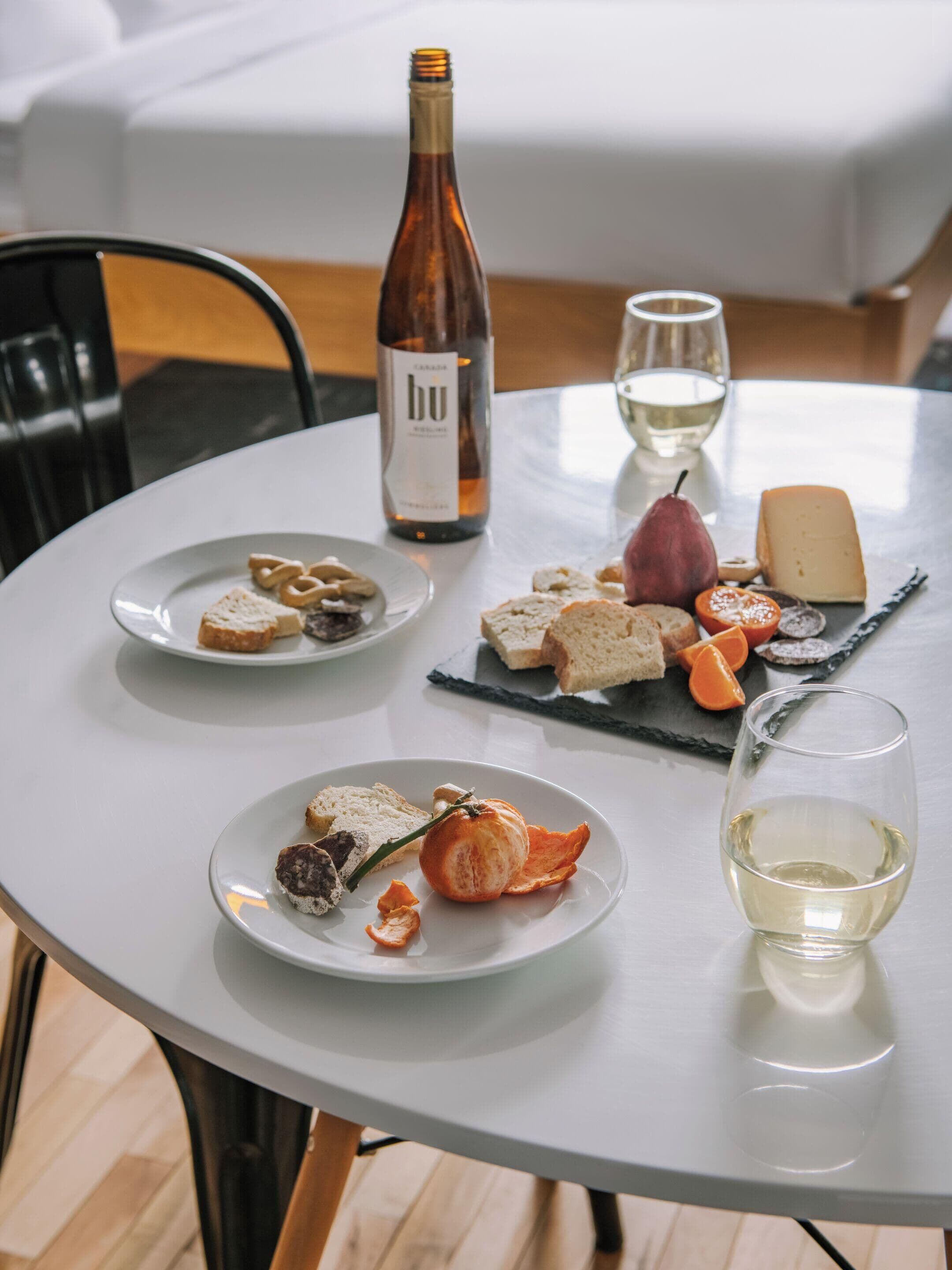 Une table ronde où sont disposés des plats, une bouteille de vin et des verres.