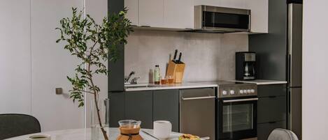 Una cocina moderna con microondas, estufa y lavavajillas. Hay una mesa de comedor con una taza, un libro y una planta.