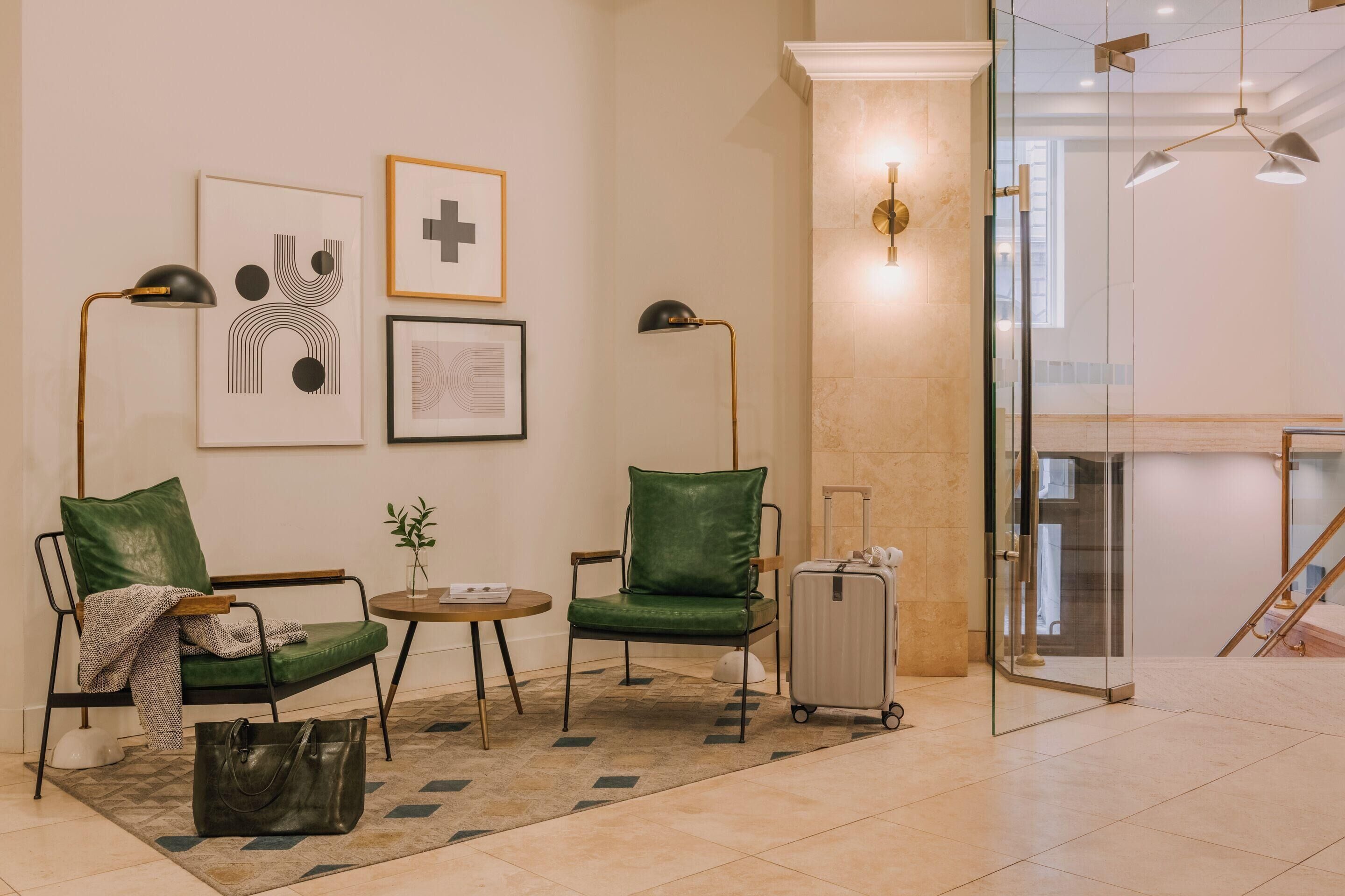 A hotel lobby with a seating area, a glass partition, and a staircase.