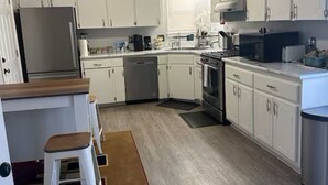 A modern kitchen with white cabinets, stainless steel appliances, and a wooden countertop. - A Home for guests on Budget. (Broken Arrow)