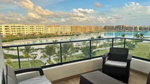 Ein Balkon mit Korbmöbeln, ein Pool und Blick auf eine Wohngegend.