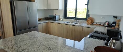 A modern kitchen with granite countertops, stainless steel appliances, and a large window providing natural light.