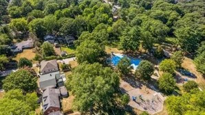 Vista aérea de uma área residencial com piscina, cercada por árvores.