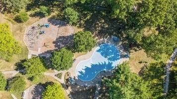 Vue aérienne d’un quartier résidentiel avec une piscine entourée d’arbres.