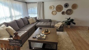 Uma sala de estar moderna com um sofá seccional, uma mesa de centro e pratos decorativos na parede.