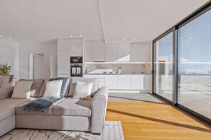 A modern living room with a sofa, a wooden coffee table, and a kitchen in the background. - Atlantic Bloom by Homie (Funchal)