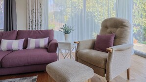 Ein Wohnzimmer mit einem violetten Sofa, einem beigen Sessel und einem kleinen Tisch.