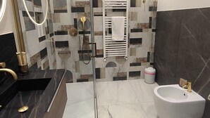 Un baño moderno con cabina de ducha de vidrio, una bañera independiente y un tocador con encimera de mármol.