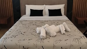 Una cama con una colcha de estampado floral, dos almohadas negras y una toalla blanca sobre la cama.