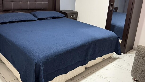 Un dormitorio con una cama grande, una mesita de noche, un armario y un espejo.