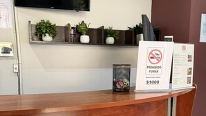Um balcão de atendimento de madeira com uma televisão fixada acima.