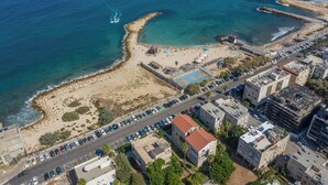 Vue aérienne d’une zone côtière avec une plage, un parking et des bâtiments.