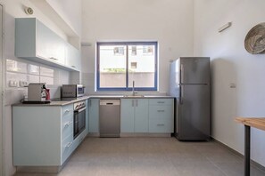 A compact kitchen with a window, a refrigerator, and modern appliances.