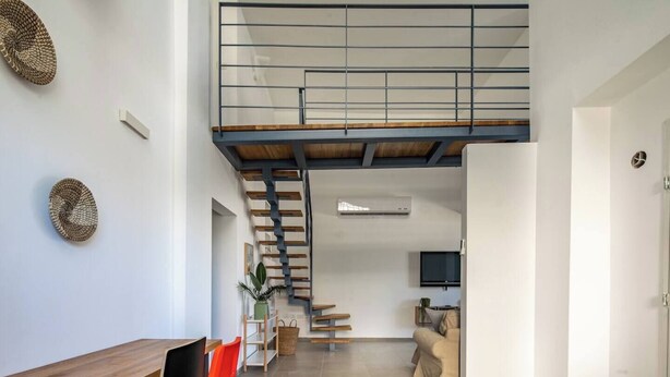 Un intérieur moderne comprenant un coin repas, un escalier menant à un niveau supérieur et un espace de vie avec un téléviseur.