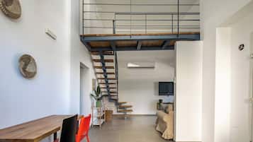 A modern interior with a dining area, a staircase leading to an upper level, and a living space with a television.