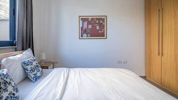 A hotel room with a bed, a nightstand, a lamp, a wardrobe, and a wall with a framed picture.