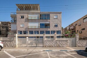 Ein mehrstöckiges Gebäude mit geschlossenem Eingangsbereich, einer flachen Dachterrasse mit Solarpanels und einer Ziegel Fassade.