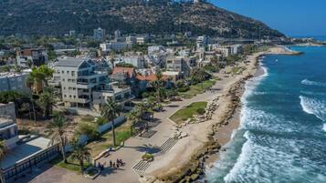 A coastal urban area with modern buildings, a beach, and rocky coastline.