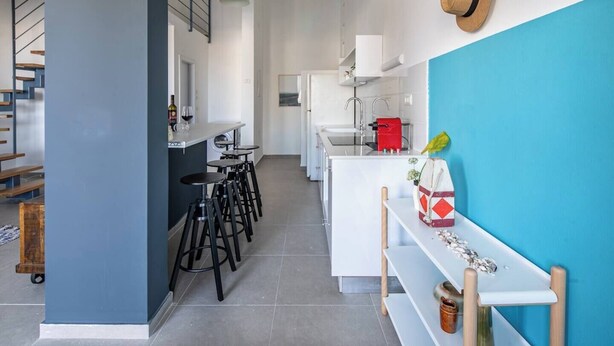 Une cuisine moderne avec un coin bar, une table à manger et un mur d’accent bleu.