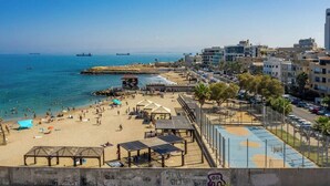 Une plage avec un rivage sablonneux, une jetée et une vue sur la ville en arrière-plan.
