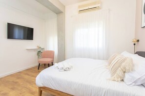 A bedroom with a bed, a chair, a TV, and an air conditioning unit. - Port city haifa- studio next to the beach & rambam (Haifa)