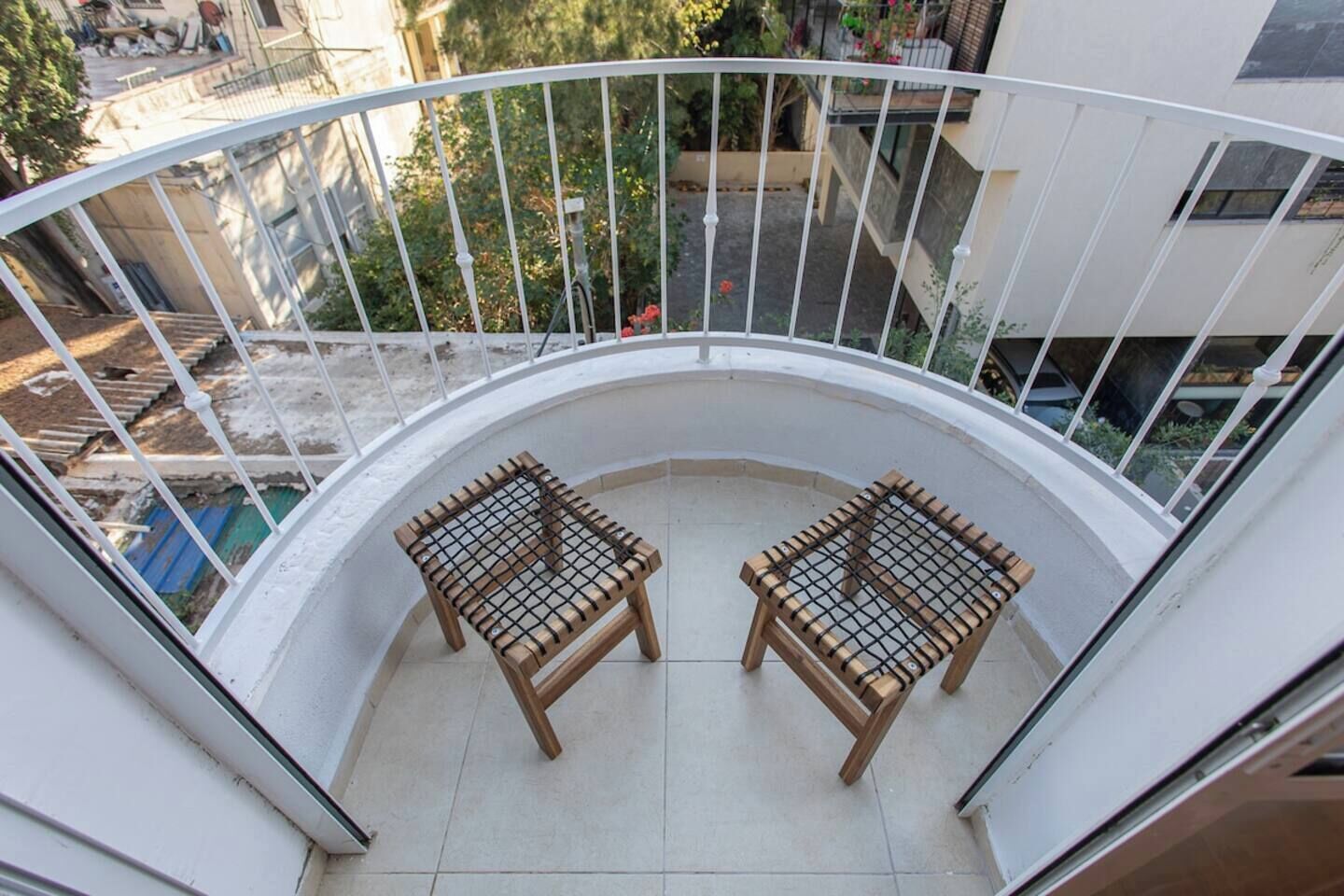 A balcony with two wooden chairs and a white railing.