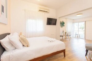 Ein Hotelzimmer mit Bett, Fernseher, Essbereich und Balkon.
