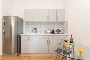 A compact kitchen with a stainless steel refrigerator, a microwave, and a kettle on the countertop. - Port city haifa-studio w/ balcony near the beach 1 (Haifa)
