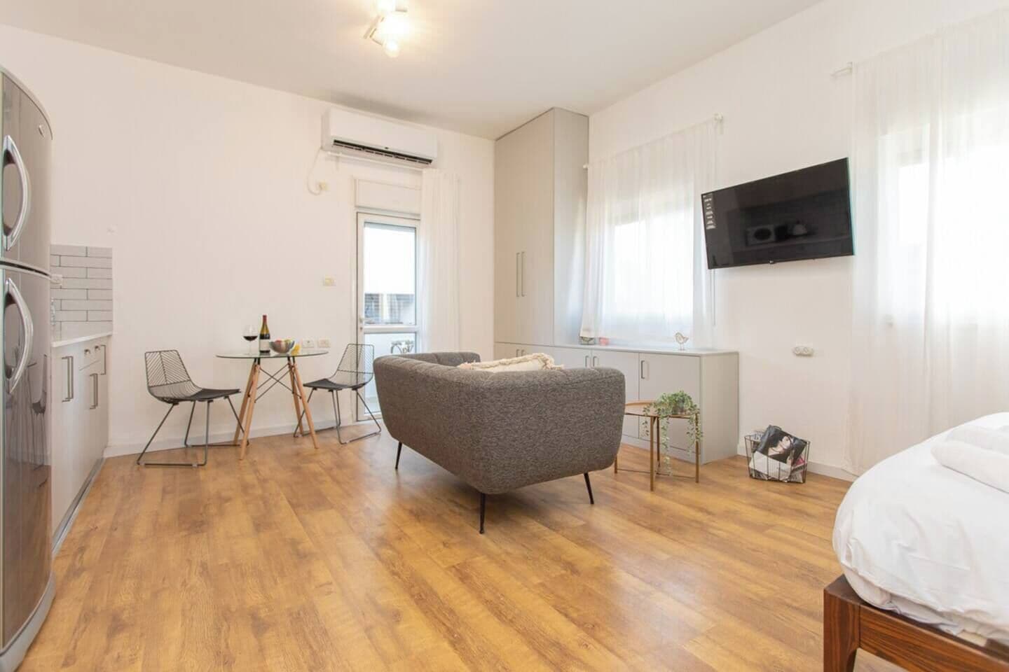 A modern apartment with a dining area, kitchenette, and a grey sofa.