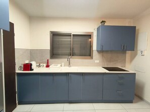 Een keuken met een wit aanrecht, een spoelbak en blauwe kastjes.