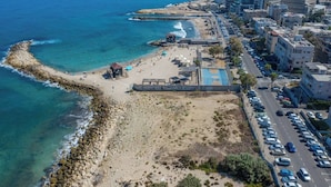A coastal cityscape with a beach, rocky shoreline, and urban buildings. - Port city haifa - 1 bdrm apt Near beach 2 (Haifa)