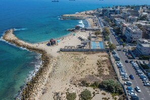 A coastal cityscape with a beach, rocky shoreline, and urban buildings. - Port city haifa - 1 bdrm apt Near beach 2 (Haifa)