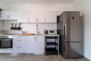 A modern kitchen with white cabinets, a stainless steel refrigerator, a microwave, and a stove. - Port city-german colony 2 bdrms w/balconymamad 3 (Haifa)