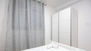 Ein Schlafzimmer mit einem Bett, einem großen Spiegel und einem Vorhang.