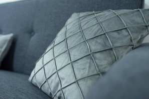 A close-up of a grey sofa with a quilted pillow.