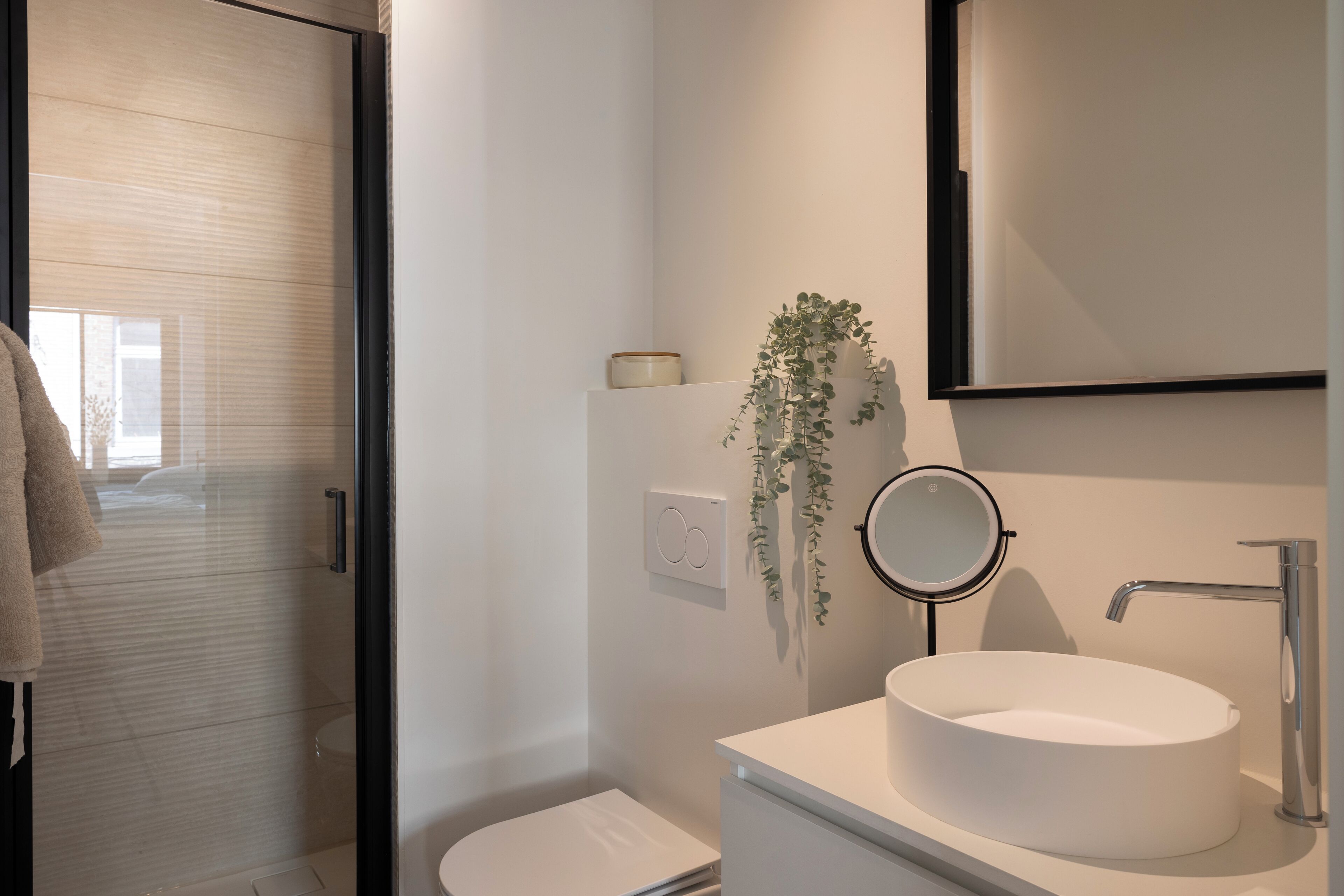 A modern bathroom with a glass shower enclosure, a white sink, and a mirror.