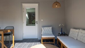 A compact living space with a door, a bench, a small table, and a hanging light fixture. - Huys17 (Hasselt)