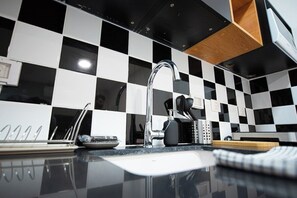 A kitchen with a black and white checkered backsplash, a stainless steel sink, and modern appliances. - Port city- Downtown 2 bdrms apt w/balcony+mamad 2 (Haifa)