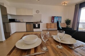 A modern kitchen with white cabinets, a dining table set with plates, glasses, and cutlery. - Port city- 1 bdrm apt w/ balcony beachfront+ mamak (Haifa)