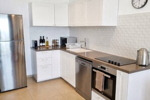 A modern kitchen with white cabinets, stainless steel appliances, and a tiled backsplash. - Port city- 1 bdrm apt w/ balcony beachfront+ mamak (Haifa)