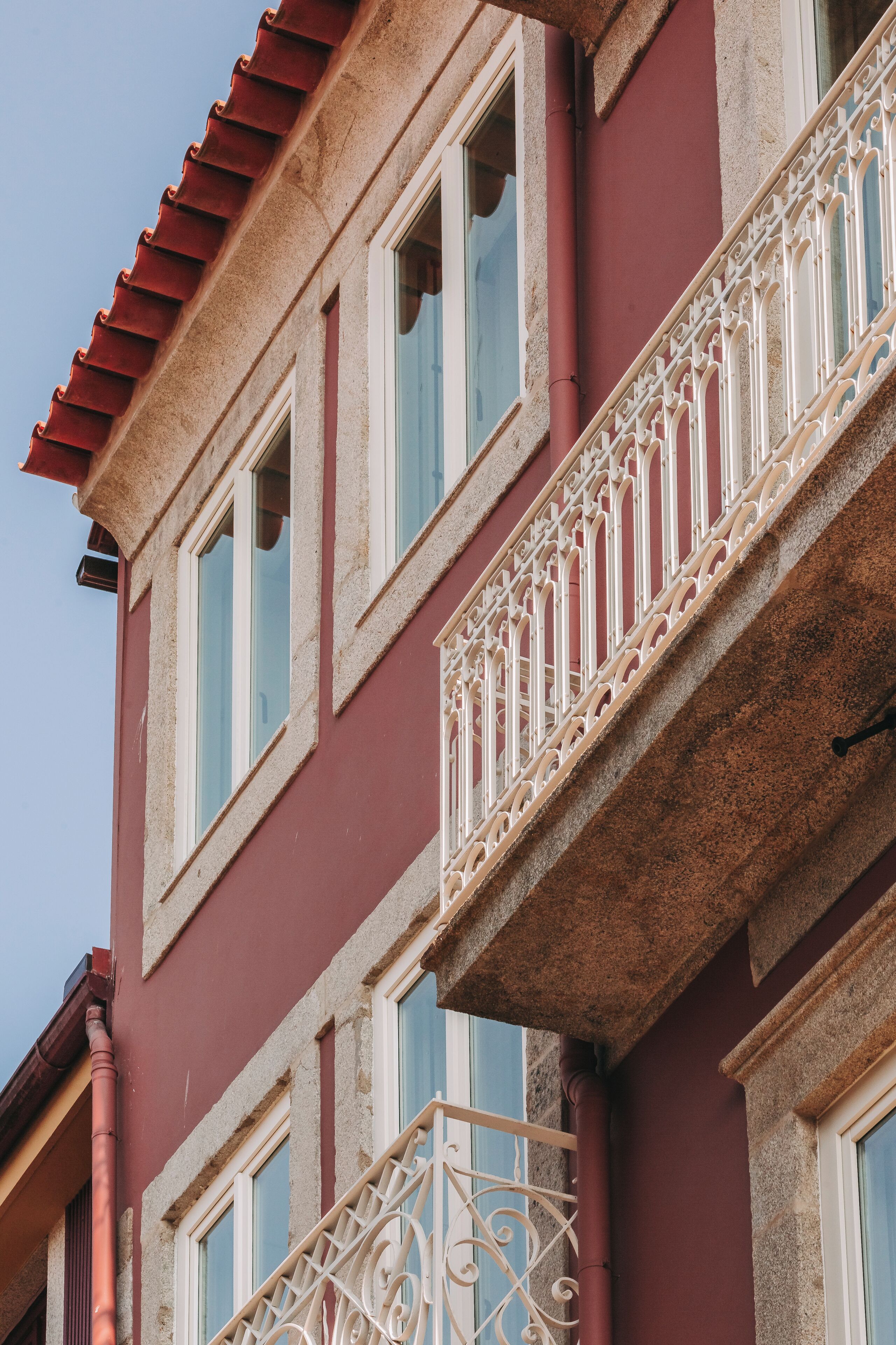 A building with a red facade, white window frames, and ornate white balconies.