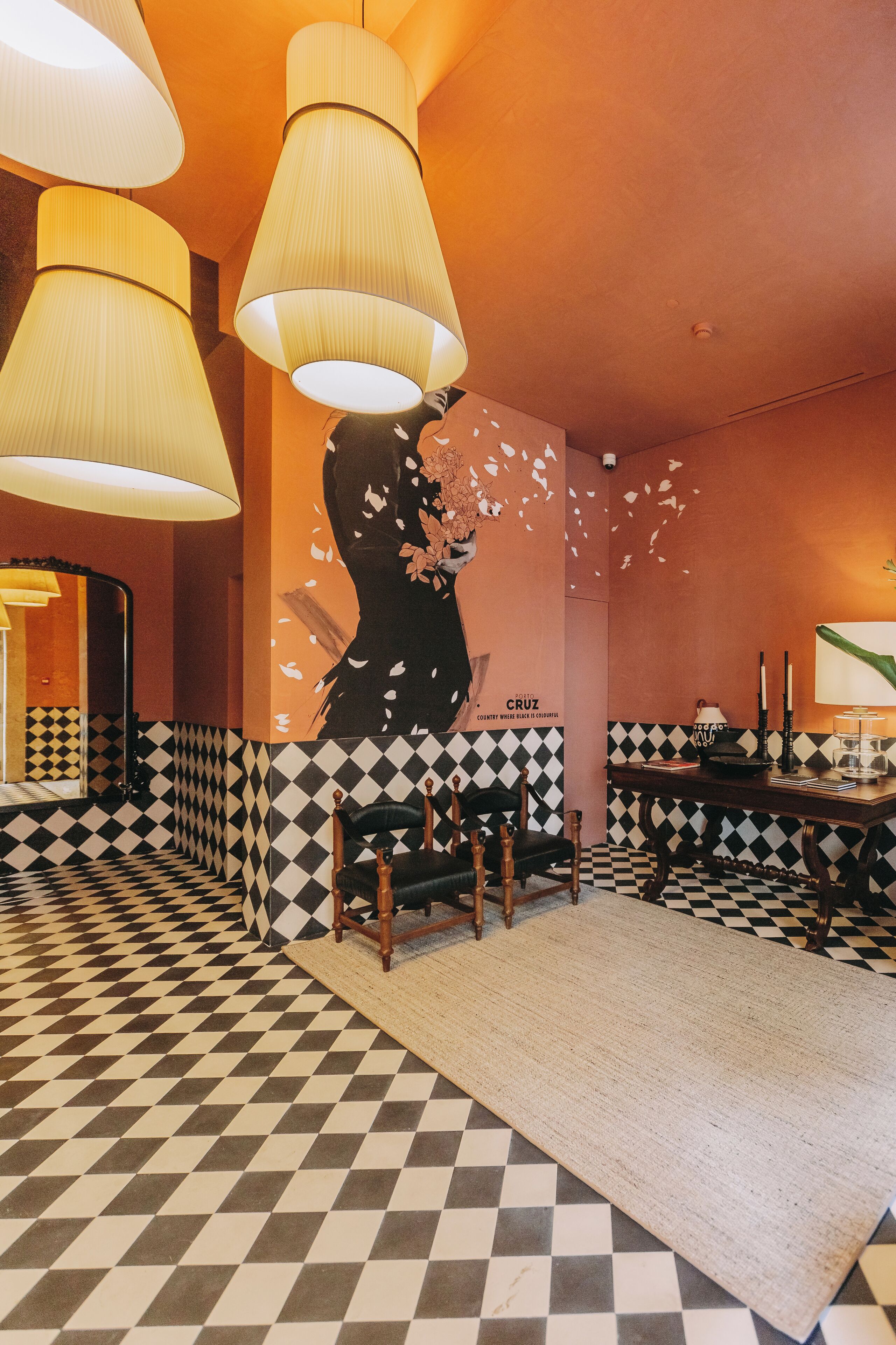 A room with a checkered floor, a large wall mural, and a seating area with a rug.
