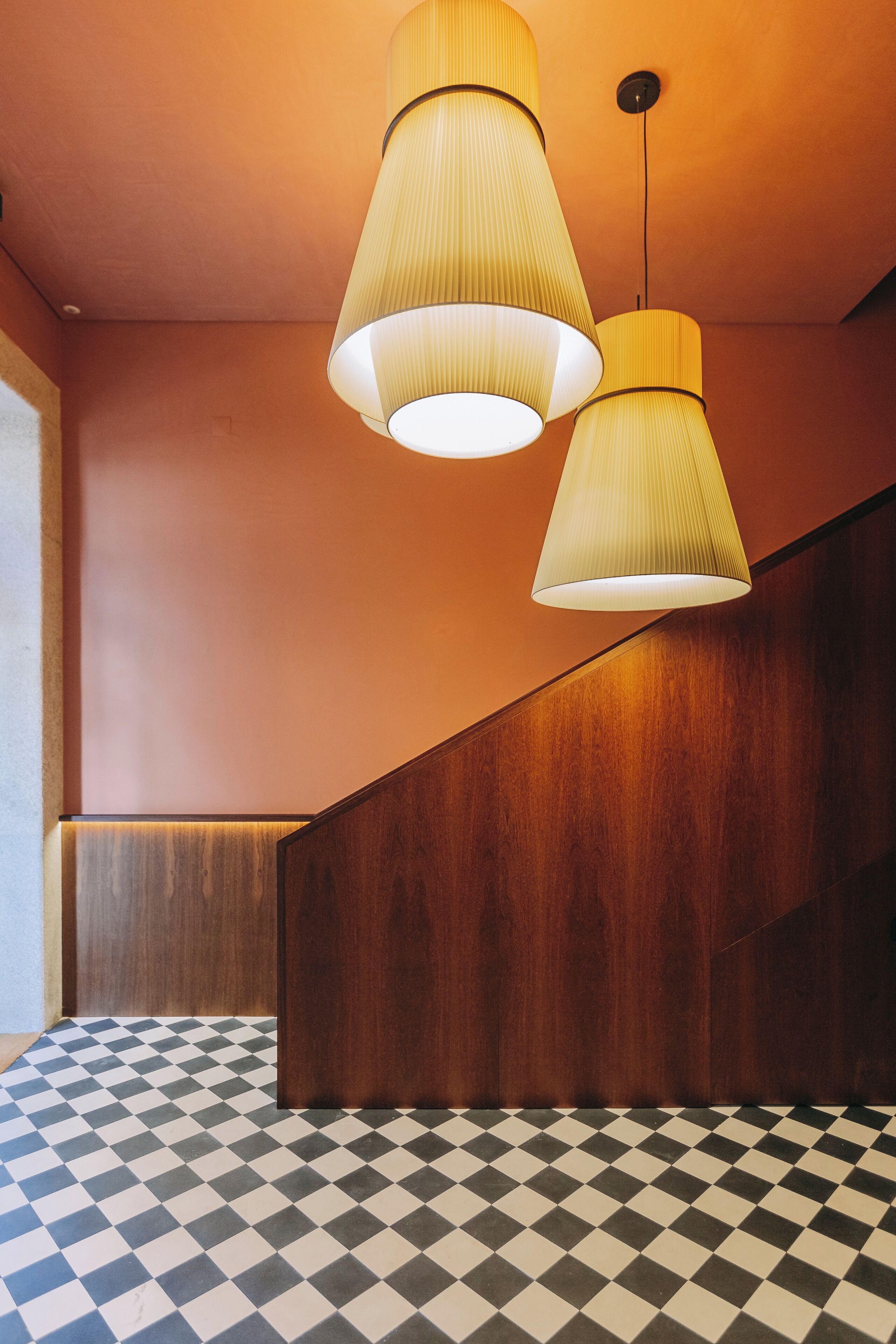 Ein modernes Interieur mit Schachbrettfußboden, Holzvertäfelung und zwei hängenden Pendelleuchten.