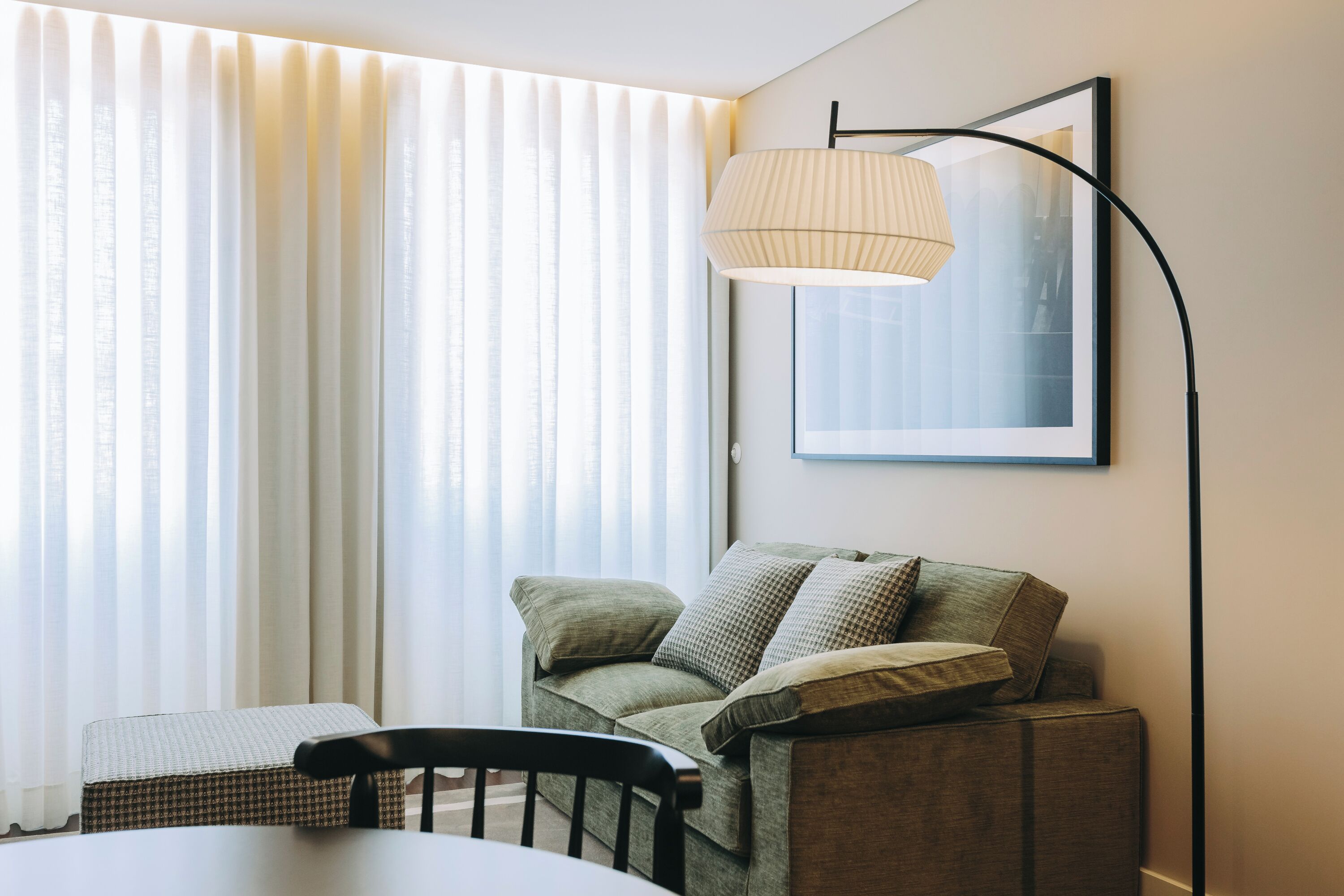 Ett modernt vardagsrum med en soffa, ett matbord och en golvlampa.