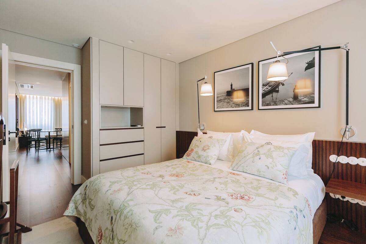 Een slaapkamer met een bed, een bureau en een stoel. Twee ingelijste foto's hangen aan de muur.