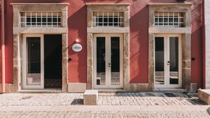 A building with two doors and a window, a sign reading "CRUZ", and a small outdoor area with a bench.